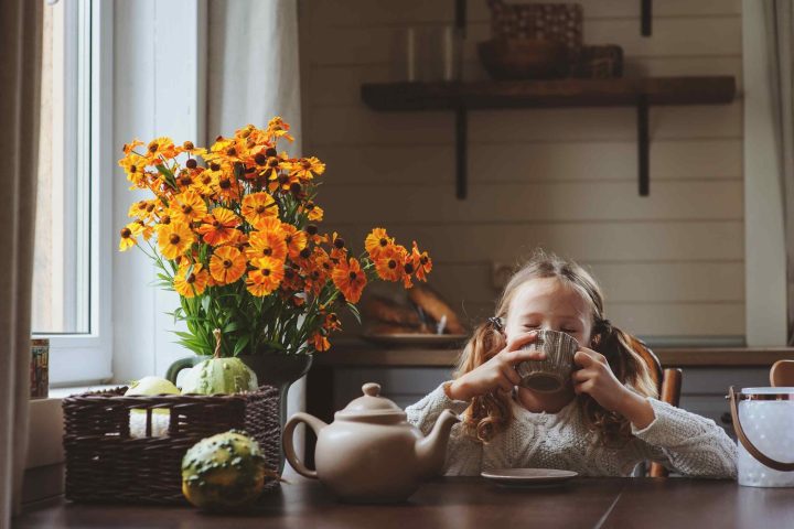 Girl sipping tea from cup at table